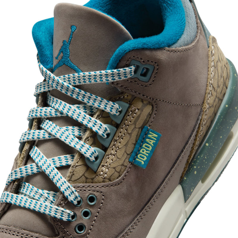 Youth Jordan sneaker close-up, teal laces, Jumpman tag, and brown suede panel
