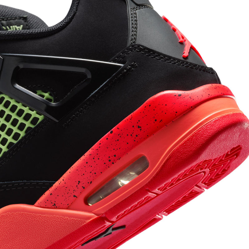 Youth sneaker close-up with black upper, neon green panel, red midsole window