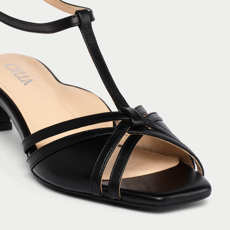 Black sandal with multiple straps on a light gray background