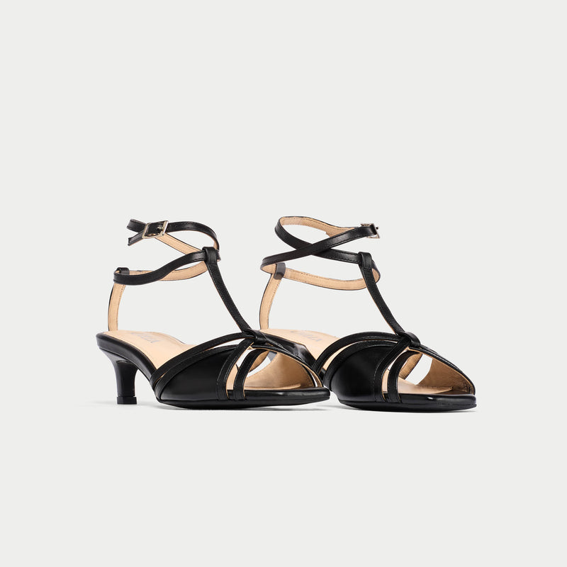 Pair of black kitten-heeled sandals on a light gray background