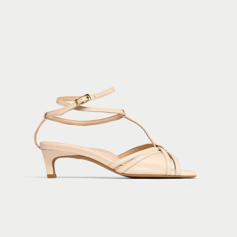Beige sandal with thin straps on a light beige background