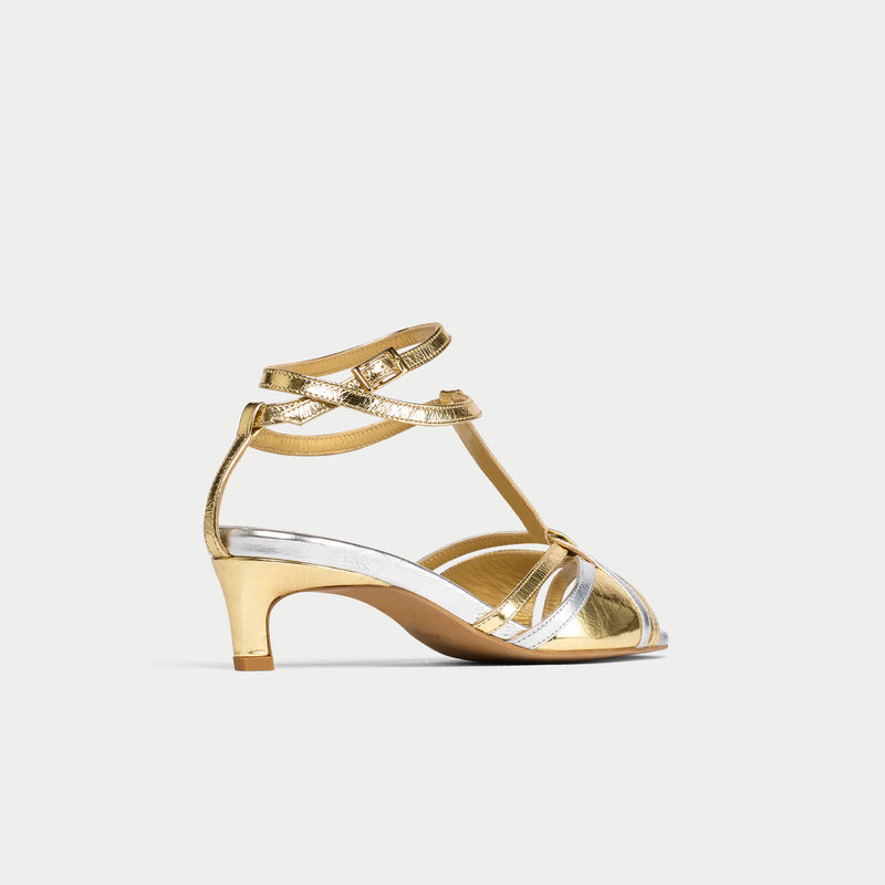 Gold kitten-heeled shoe with clear strap on a white background