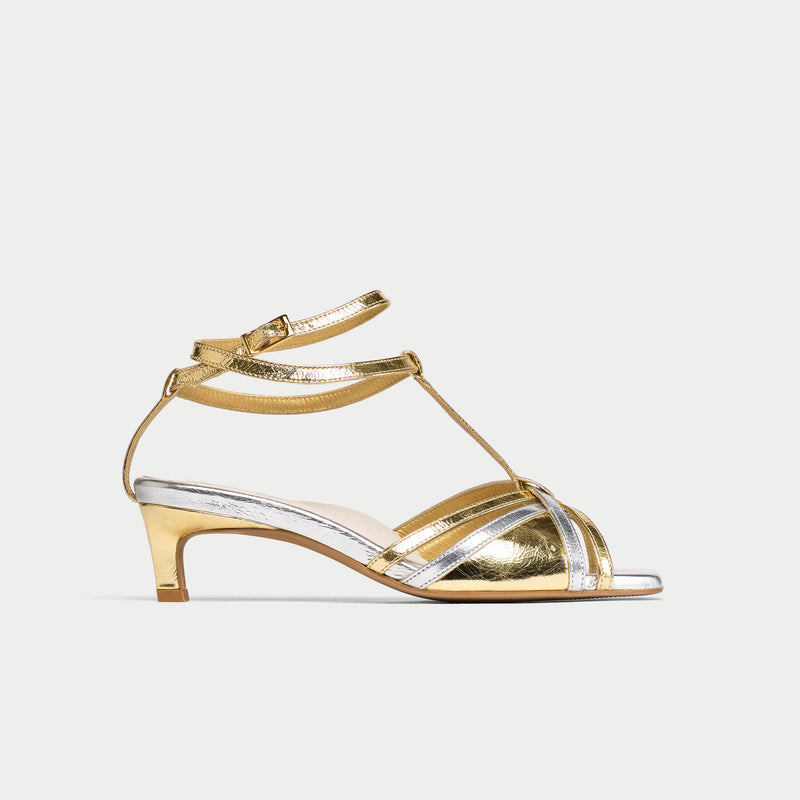 Gold sandal with clear straps on a light gray background
