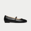 Black leather flat shoe with a strap on a light gray background