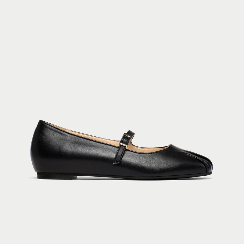 Black leather flat shoe with a strap on a light gray background