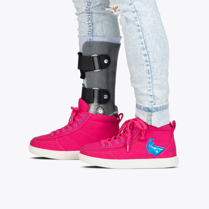 A person in light blue ripped jeans, a black leg brace, and SALE - Pink/Blue Light Ups BILLY Classic D|R High sneakers by BILLY Footwear with white soles and blue side design stands on a white background.