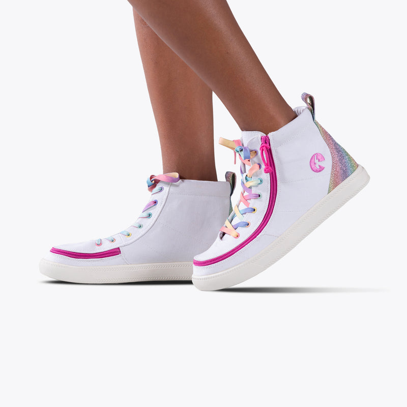 Close-up of SALE - White Rainbow BILLY Classic Lace High kids’ sneakers by BILLY Footwear, featuring rainbow laces, pink trim, glittery iridescent heel detail, and a wraparound zipper, set against a plain white background.