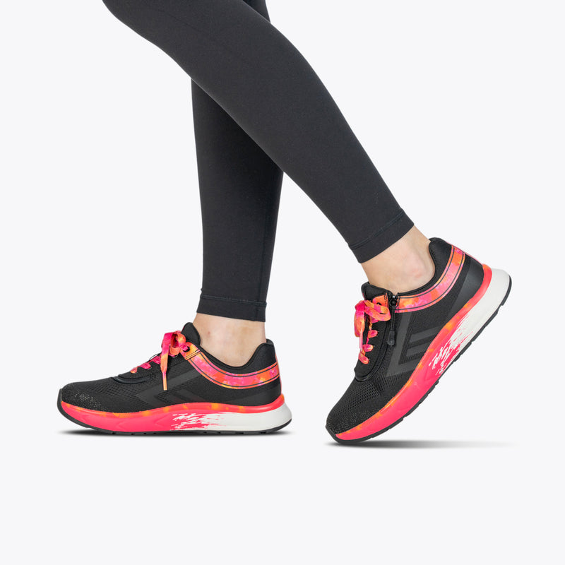 A person wearing black leggings and SALE - Women's Black/Fuchsia Fire BILLY Sport Inclusion shoes by BILLY Footwear is walking, shown from the knees down against a plain white background.