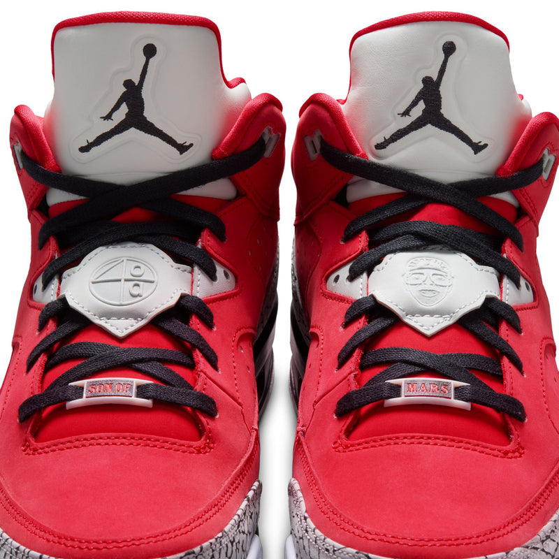 Close-up of red sneakers with black laces, white tongues, and grey speckled midsole