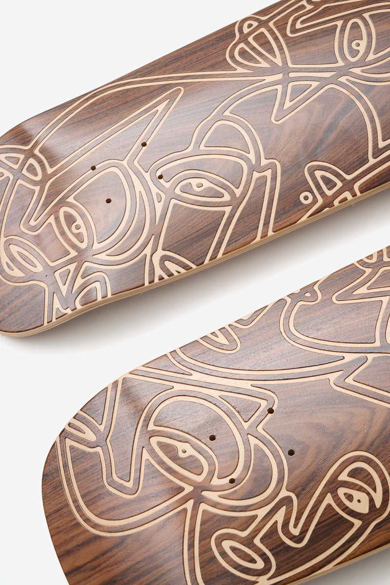 Close-up of laser etched line art on a rosewood maple skateboard deck showing intricate grain pattern