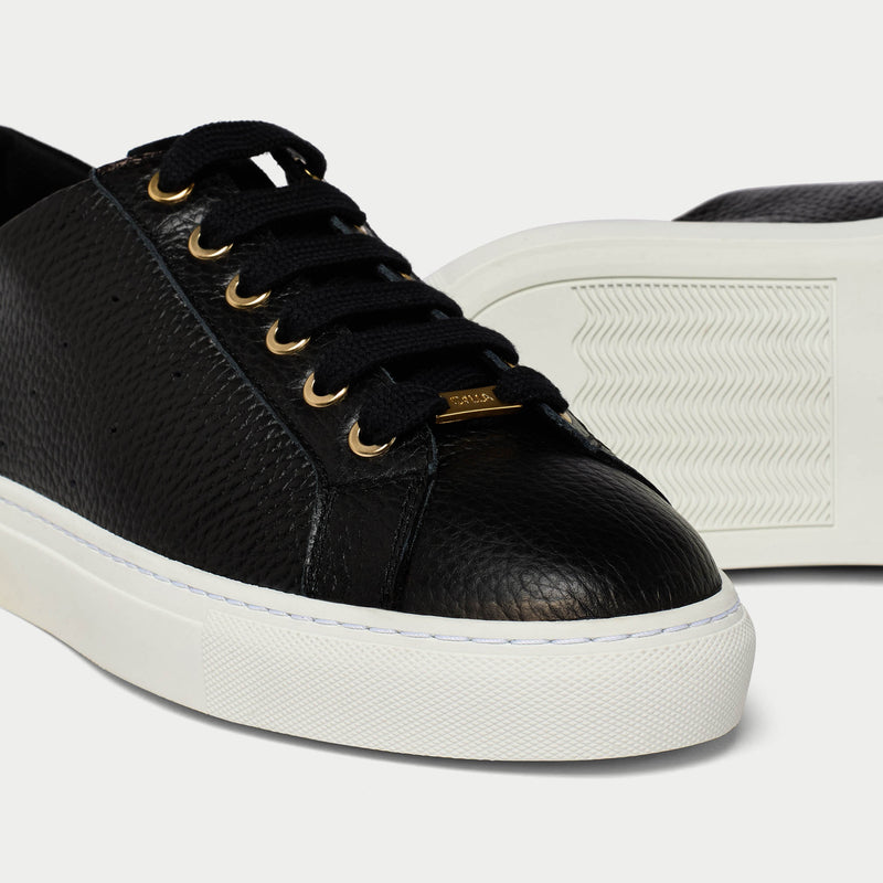 Black leather sneaker with white sole on a light gray background