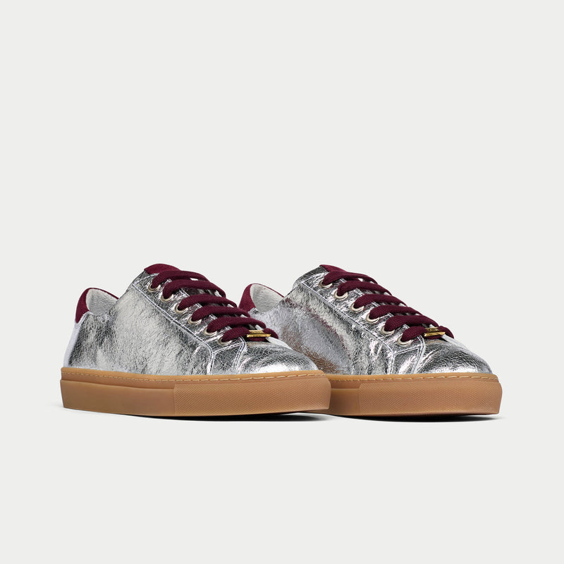 Silver star sneakers with burgundy laces on a light gray background
