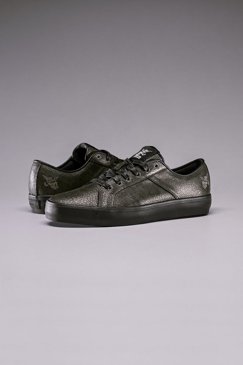 Pair of black distressed vulcanized skate shoes with textured leather and black soles.