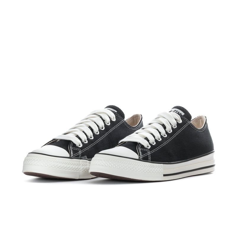 Pair of black low-top sneakers with white laces and off-white rubber soles