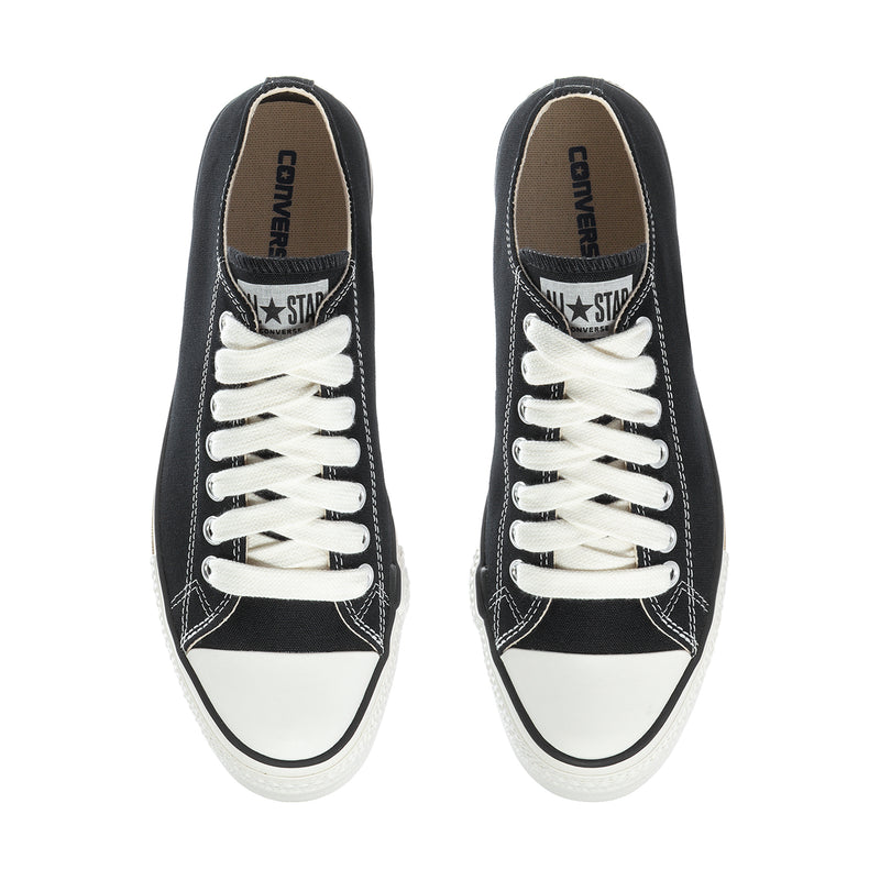 Black low-top sneakers with white laces; Converse All Star logo on inner tongue