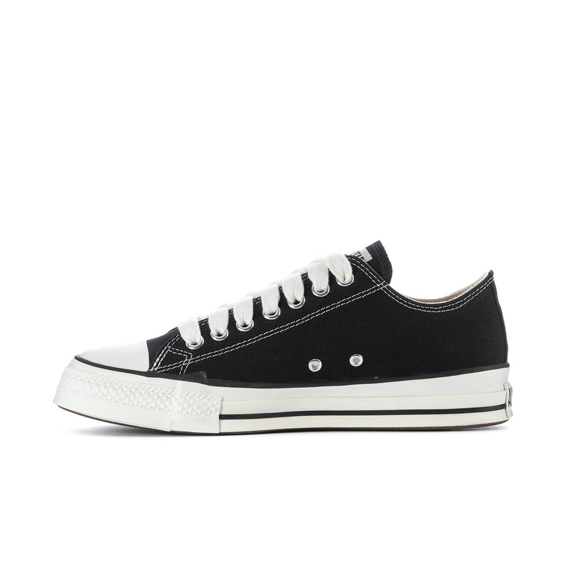 Black low-top skate sneakers with white laces, eyelets, and off-white midsole
