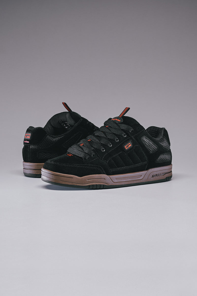 Side view of Tilt Prime black skate shoes with gum sole and orange accents
