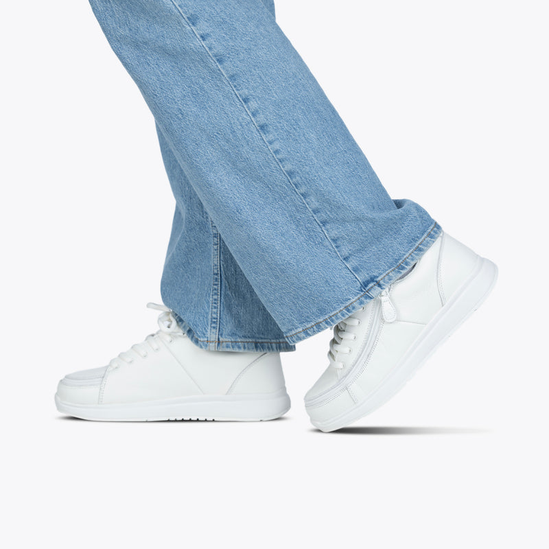 Lower legs and feet shown as a person steps forward in light blue jeans, highlighting the stylish Women's White Leather BILLY Comfort Plush shoes by BILLY Footwear against a plain white background.