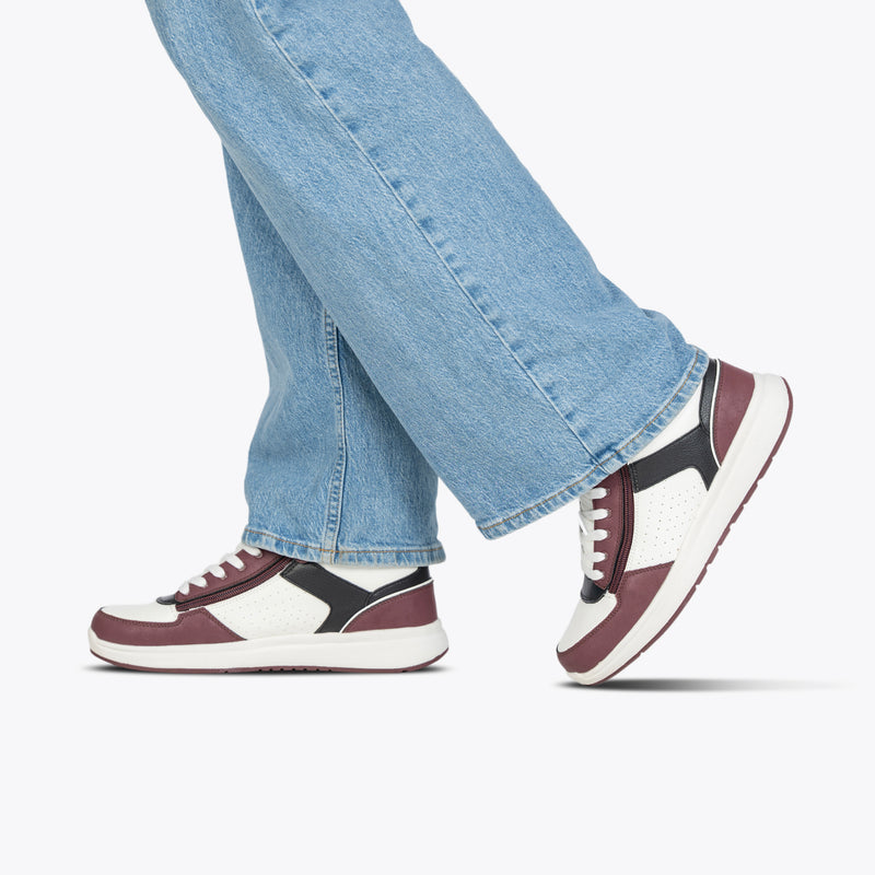 A person wearing light blue jeans and BILLY Footwear Women's White/Wine/Black BILLY Comfort DZ High sneakers steps forward against a plain white background.