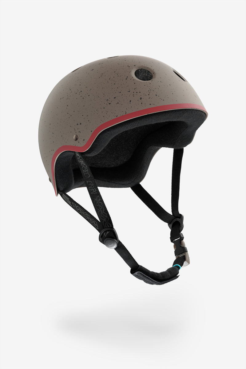 YEPA helmet in warm stone with speckled finish and red trim, side view showing foam padding and chin strap.